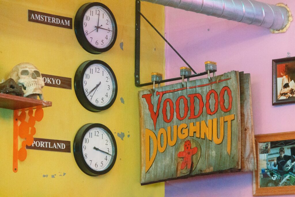 Pink and yellow walls with a VooDoo Doughnuts sign in the middle.
