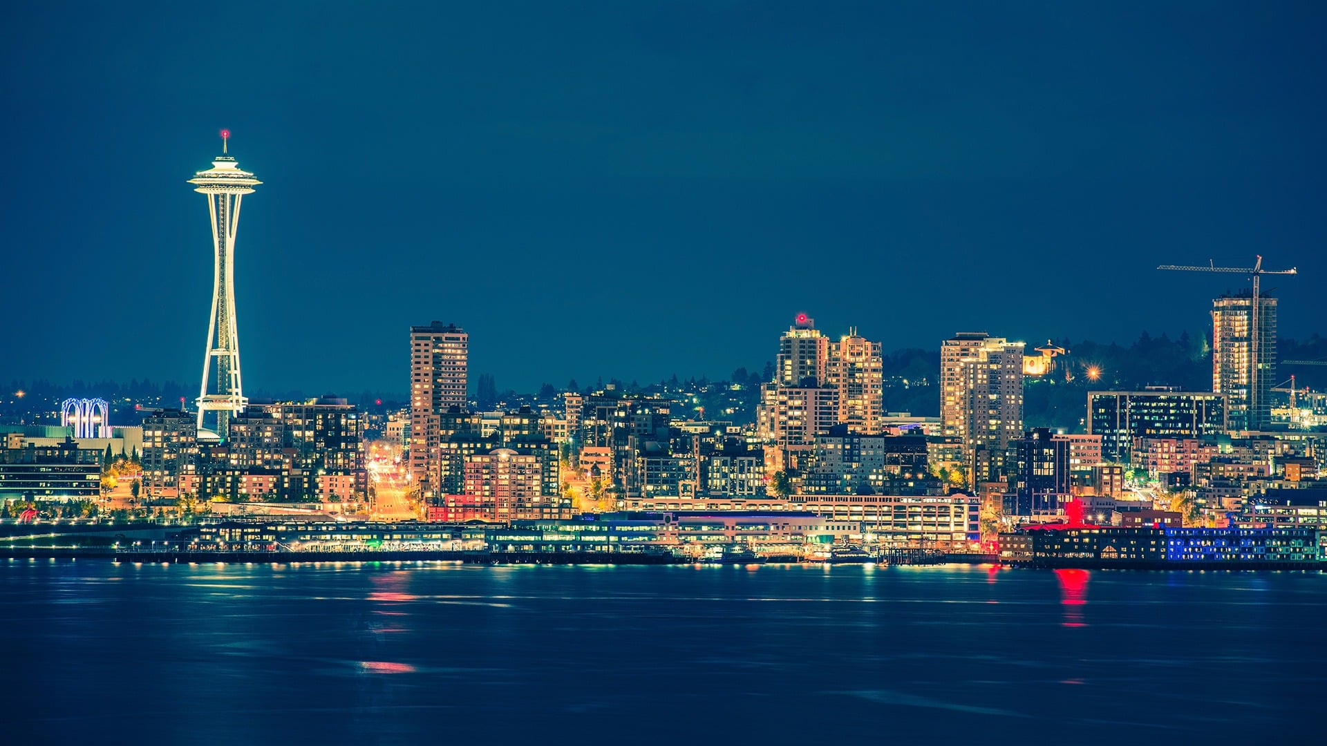 Colorful Seattle skyline reflects on the water at night.