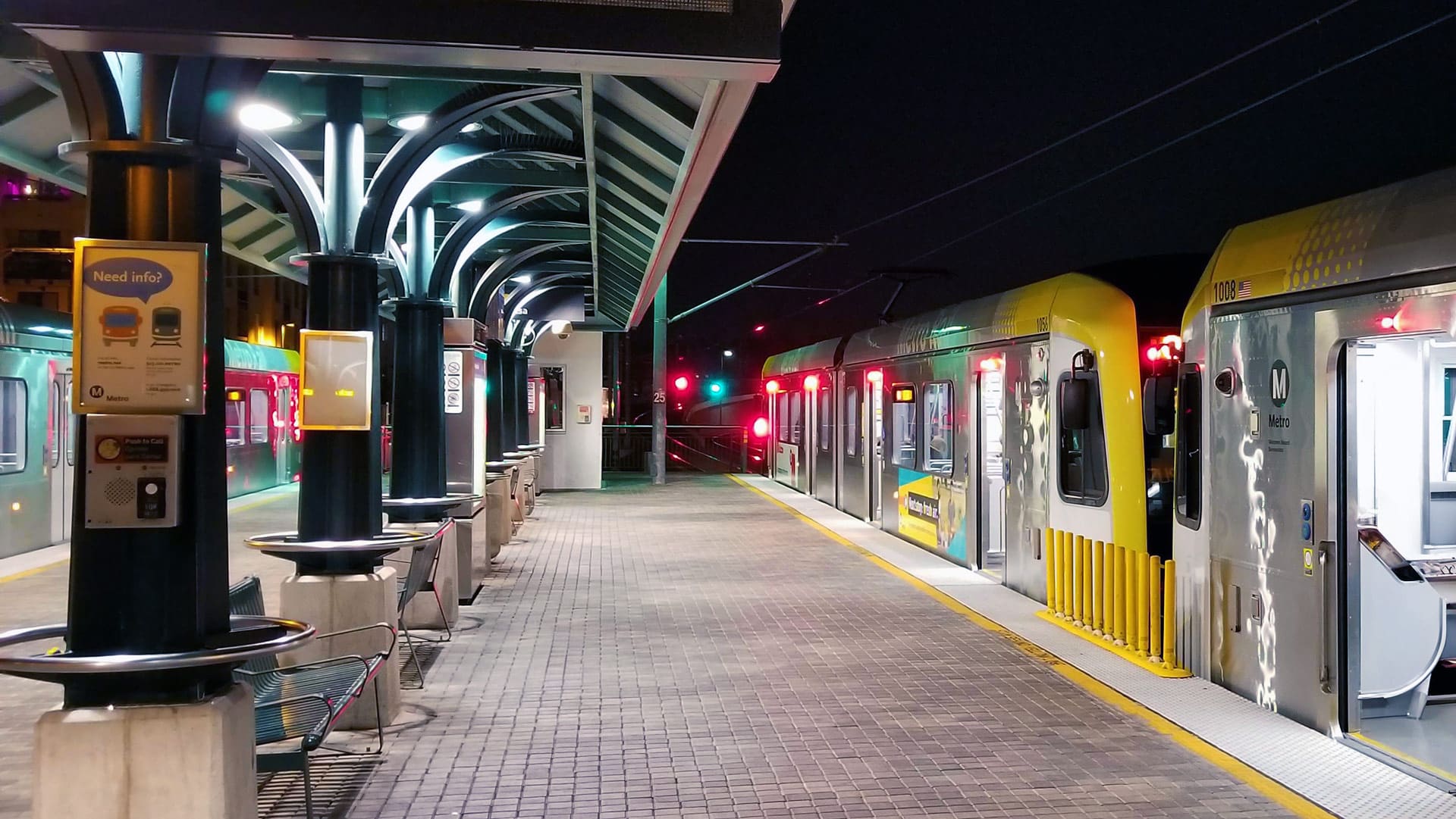 Light rail train waiting at high level brick platform for passengers.
