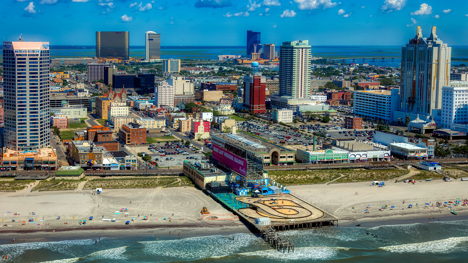 Boardwalk and beach of Atlantic City with the pier reaching out into the water.