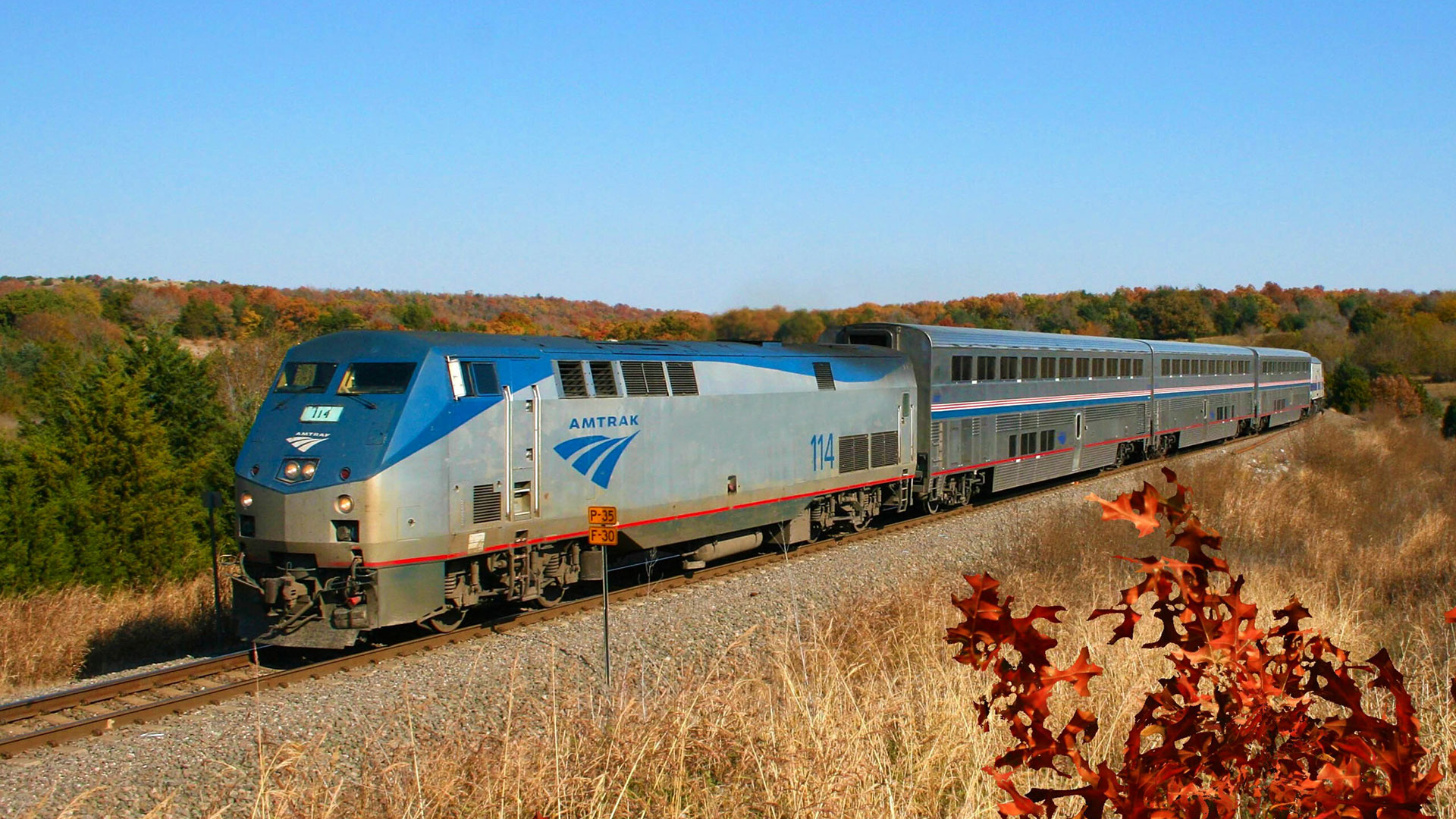 Silver and blue Amtrak train rolling through the hills of Oklahoma.