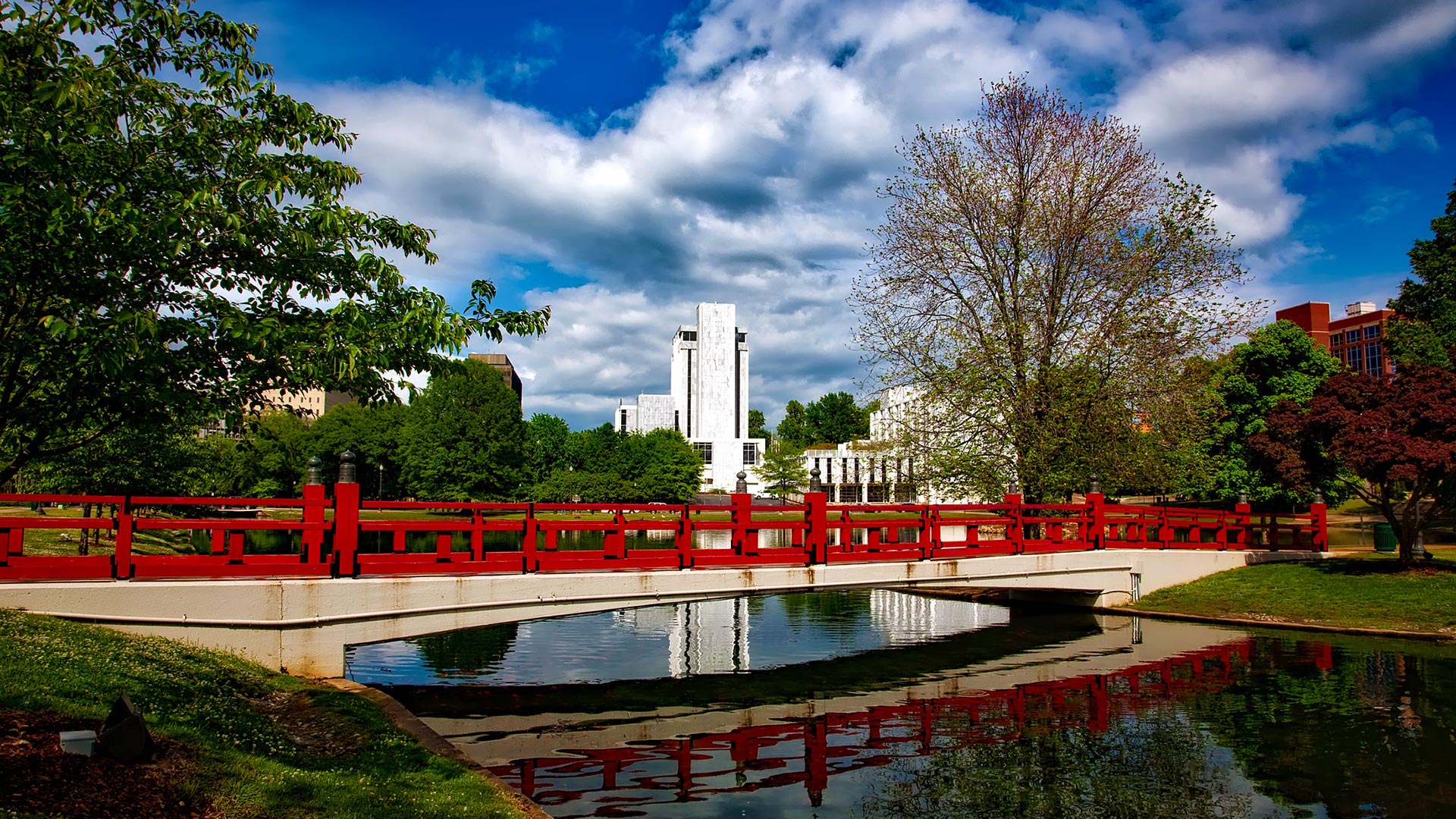 Brown and red railing bridge with a blue sky and white clouds in the background.