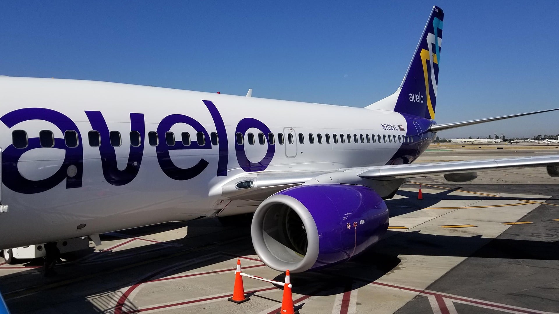 A white plane with purple accents on the tarmac.