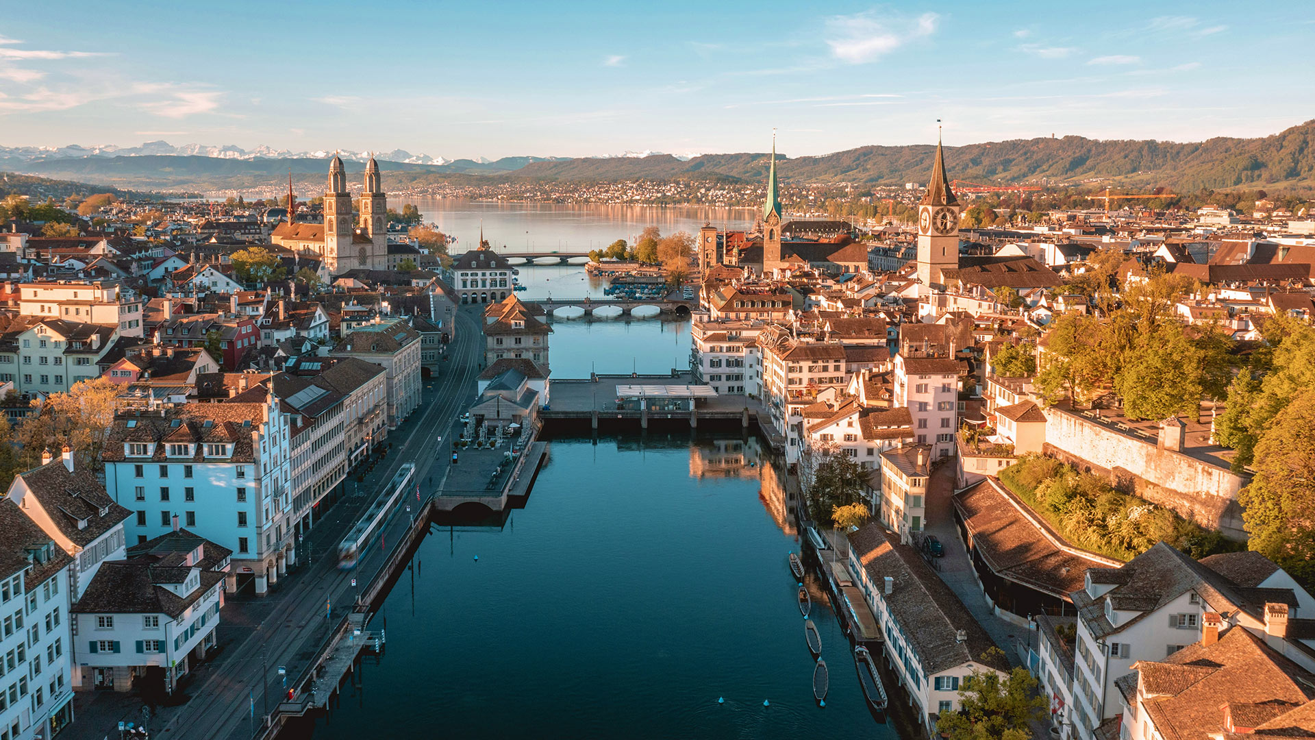 Elevated view of the city center of Zurich with multiple churches set upon a crystal blue river and lake.