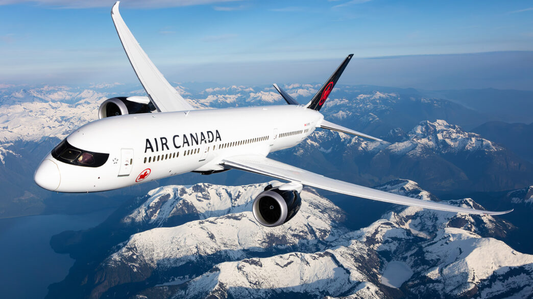 White Air Canada plane flying over snow covered mountains.