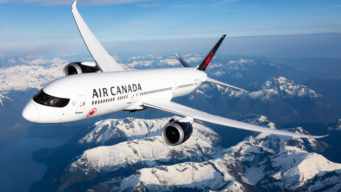 White Air Canada plane flying over snow covered mountains.