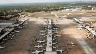 Picture of Atlanta's airport taken from the air with many planes waiting at gates below.