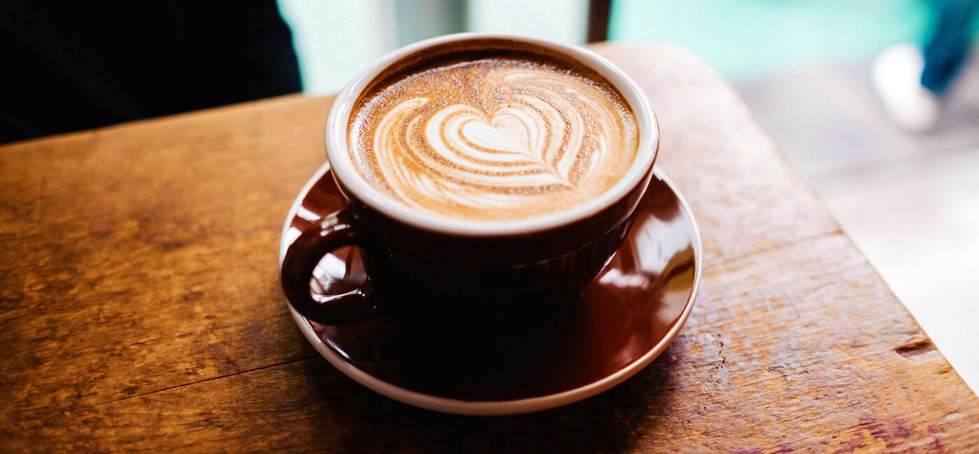 Cup of coffee sitting on a wooden table.