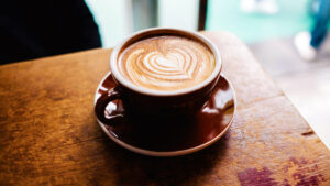 Cup of coffee sitting on a wooden table.
