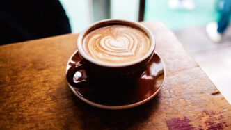Cup of coffee sitting on a wooden table.