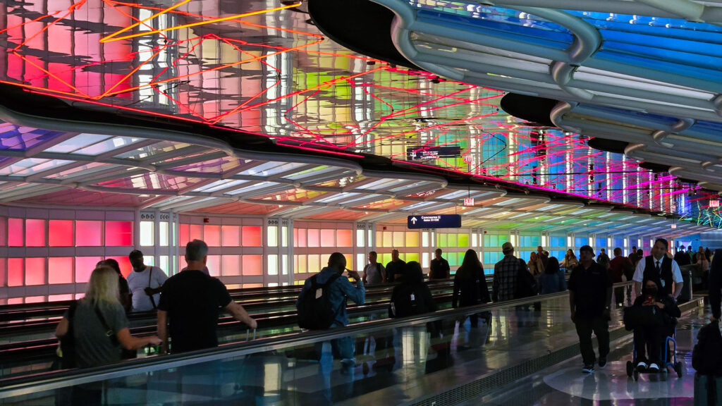 Tunnel and moving walkway at Chicago O'Hare airport with colorful lighted walls.