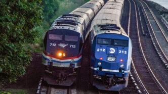 Two trains passing each other, one with a blue engine and the other a black engine.