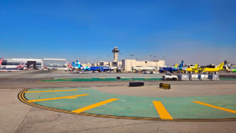 Planes in different liveries including yellow, blue, and silver stand at airport gates in Los Angeles.