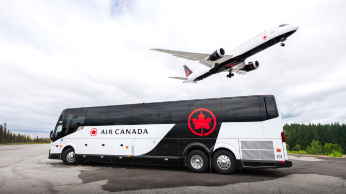 Air Canada bus in white and black livery with a Air Canada plane in white and black landing above the bus.