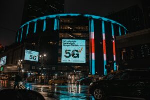 Madison Square Garden in New York City on a rainy night with neon signs shining brightly.