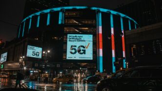 Madison Square Garden in New York City on a rainy night with neon signs shining brightly.