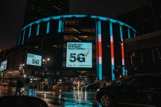Madison Square Garden in New York City on a rainy night with neon signs shining brightly.