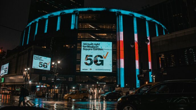 Madison Square Garden in New York City on a rainy night with neon signs shining brightly.